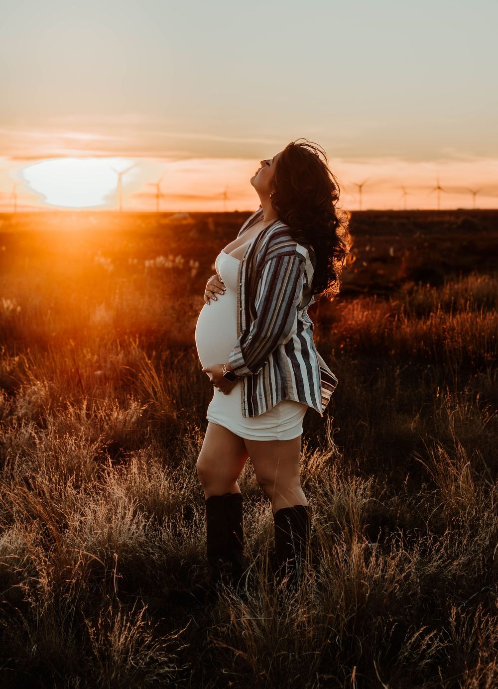 Sunset maternity session in field with dramatic orange sky.