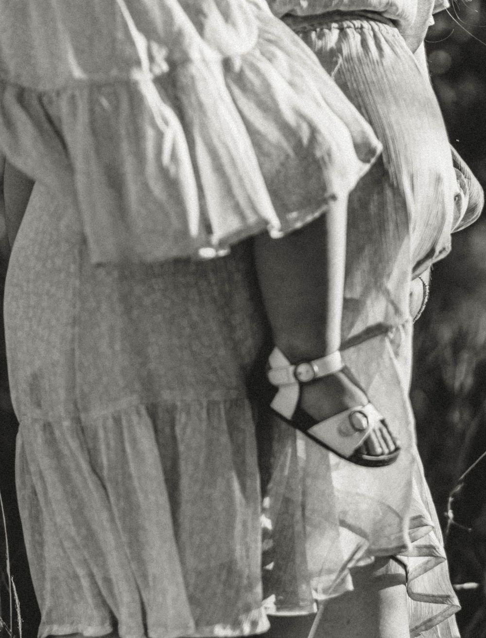 Vintage black and white photograph showing children's legs wearing white socks and buckle shoes.