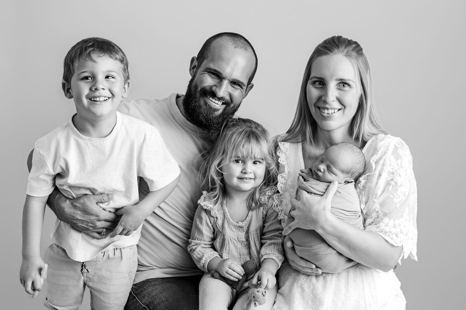 A series of black and white family portraits showing joyful moments and loving interactions between parents and children.