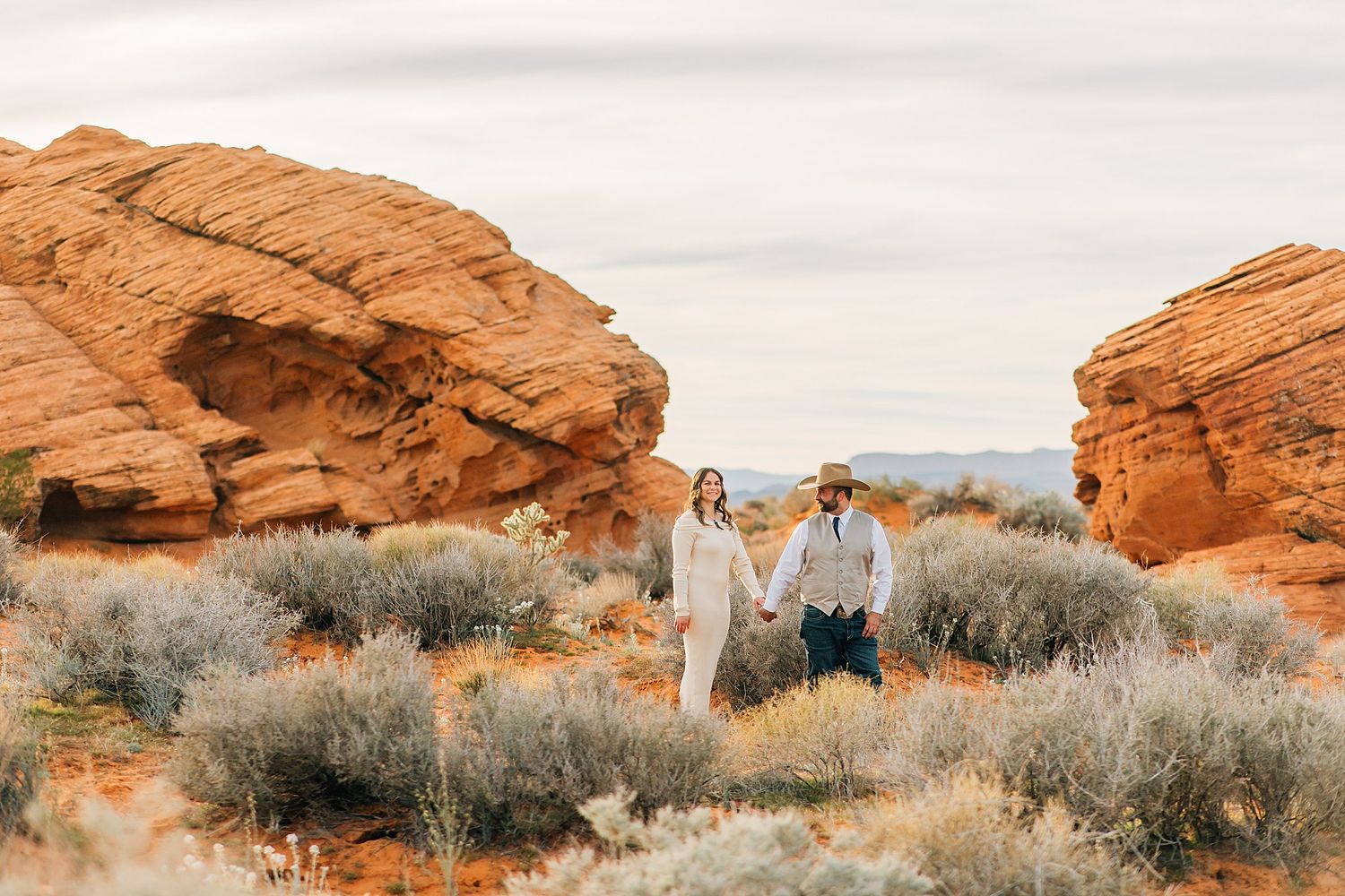 Couple poses together against stunning red rock formations at Valley of Fire State Park during sunset.