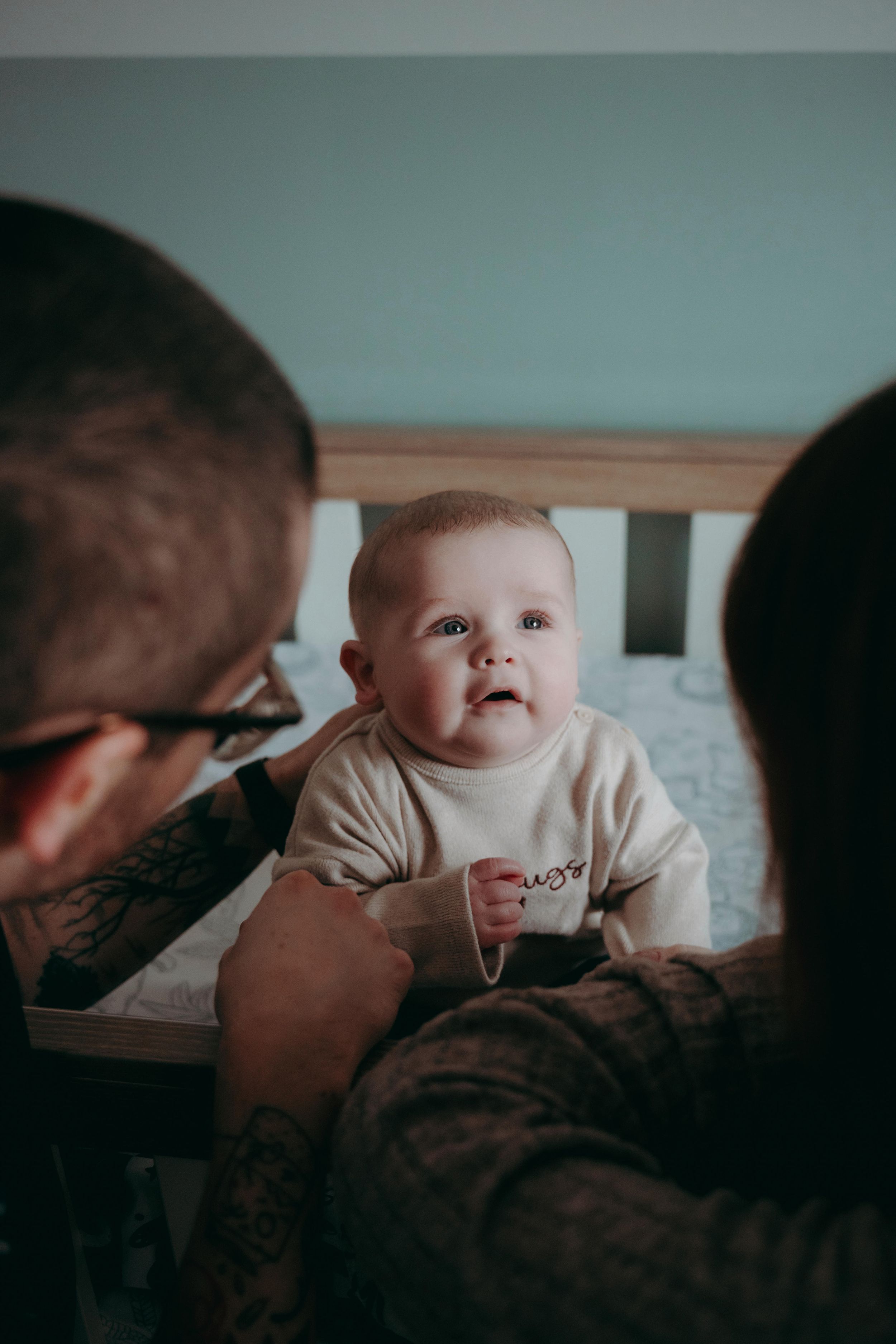 A tender sequence showing an adult and baby sharing intimate moments together in a dimly lit room.