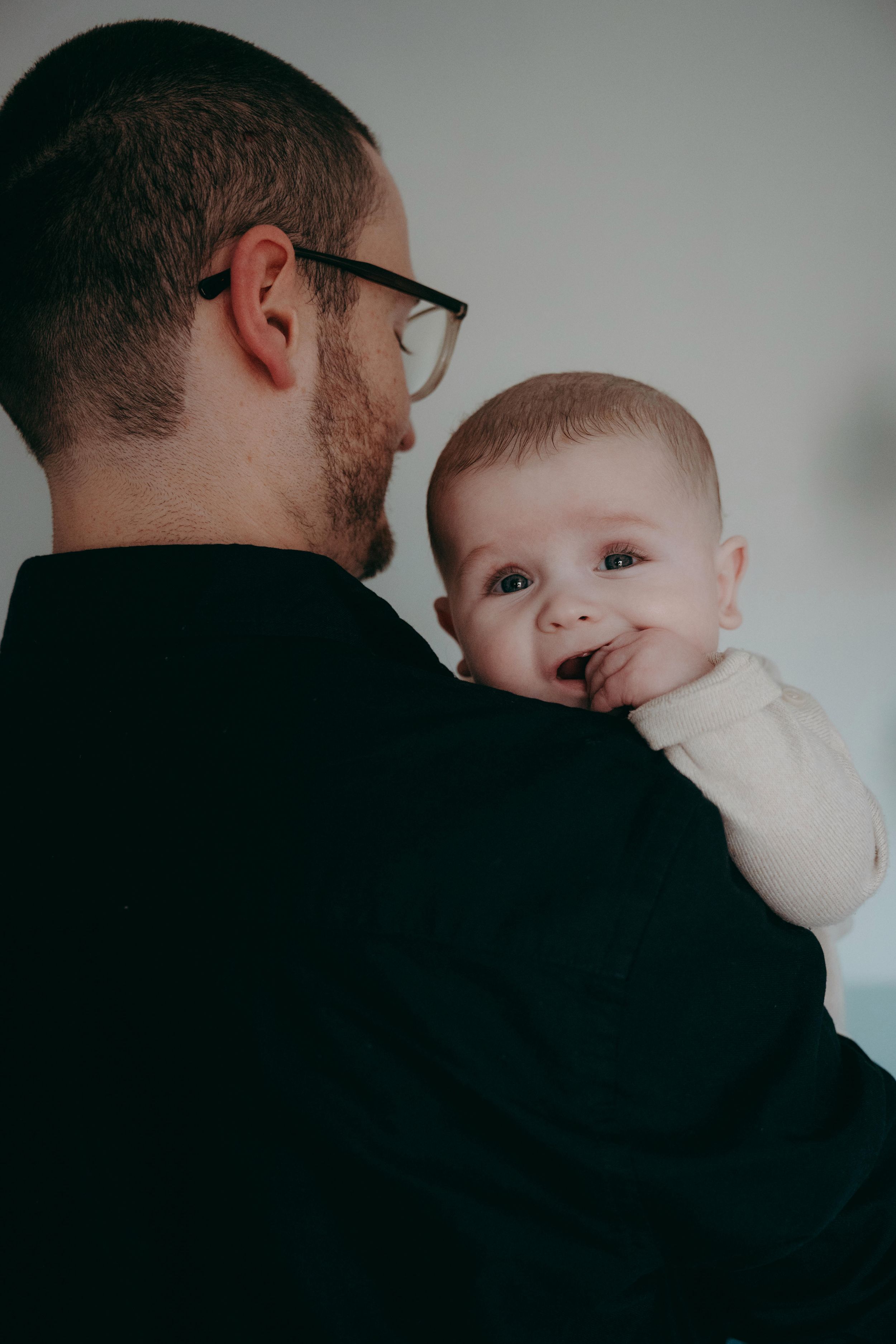 A tender moment between a parent in a black sweater and their baby shown in a series of intimate close-up shots.