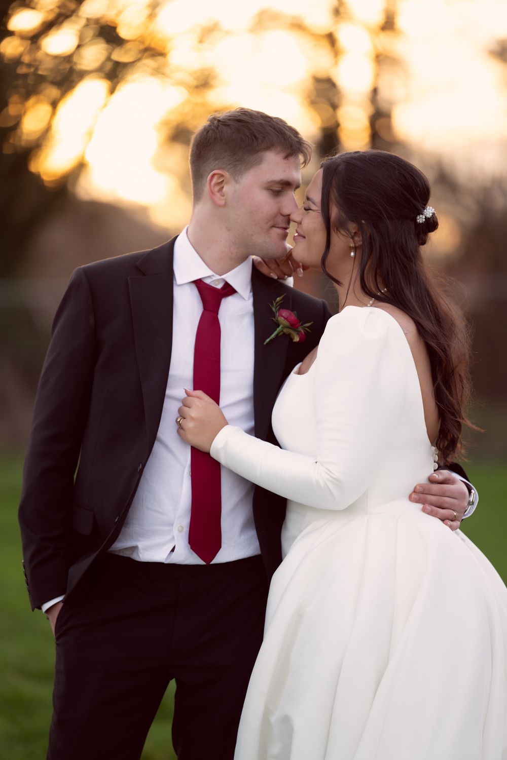 A romantic wedding photo series showing a couple in formal attire embracing during sunset in an outdoor setting.