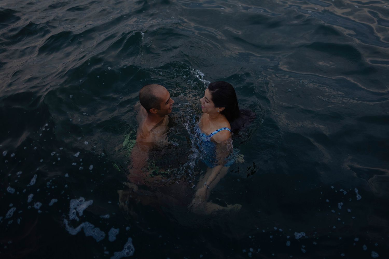 couple swims in lake ontario near kingston ontario during Novella portrait session, at sunset