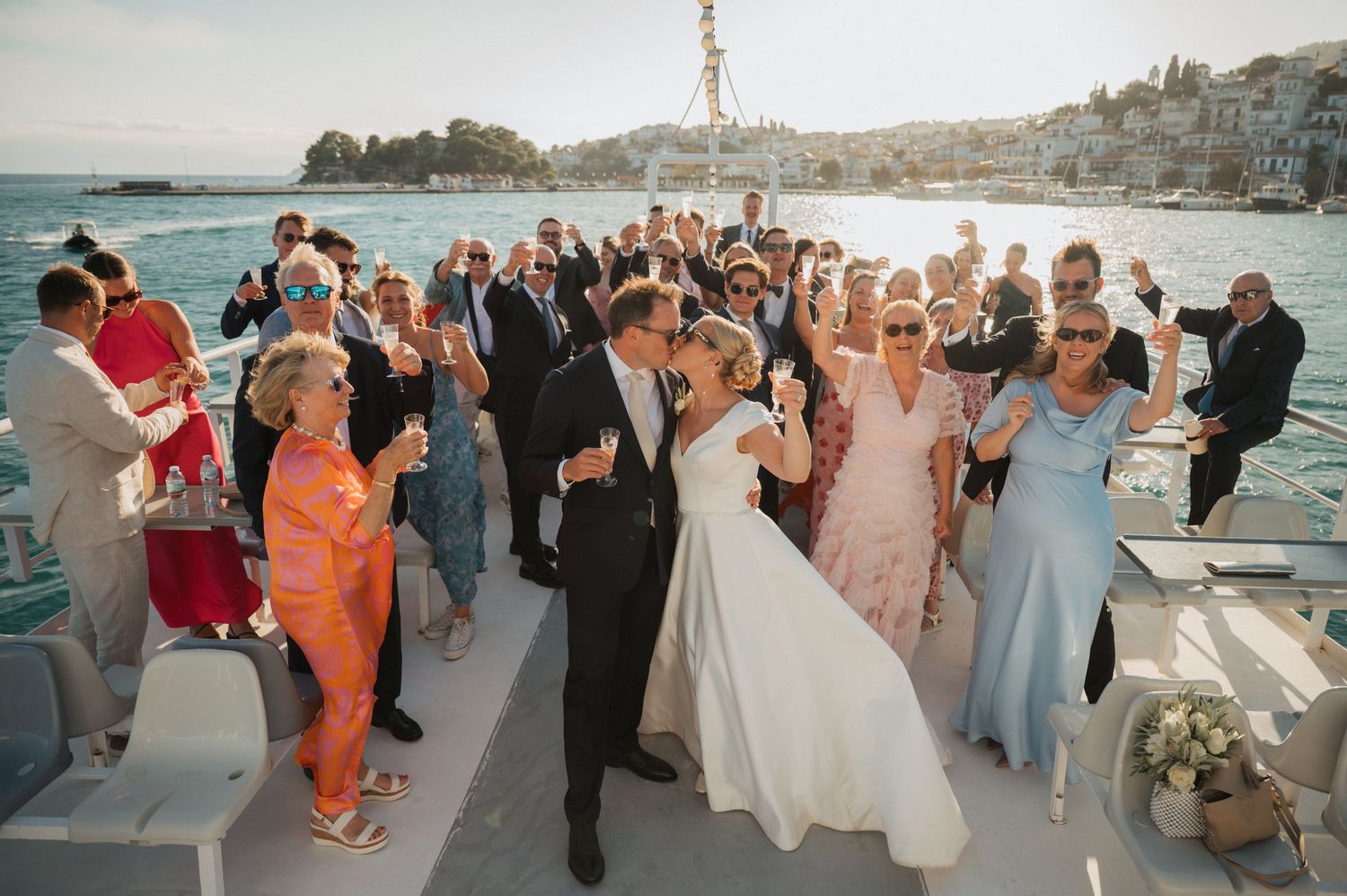 Scenic wedding photos on a Mediterranean balcony overlooking a harbor with vibrant pink bougainvillea flowers and boats below.