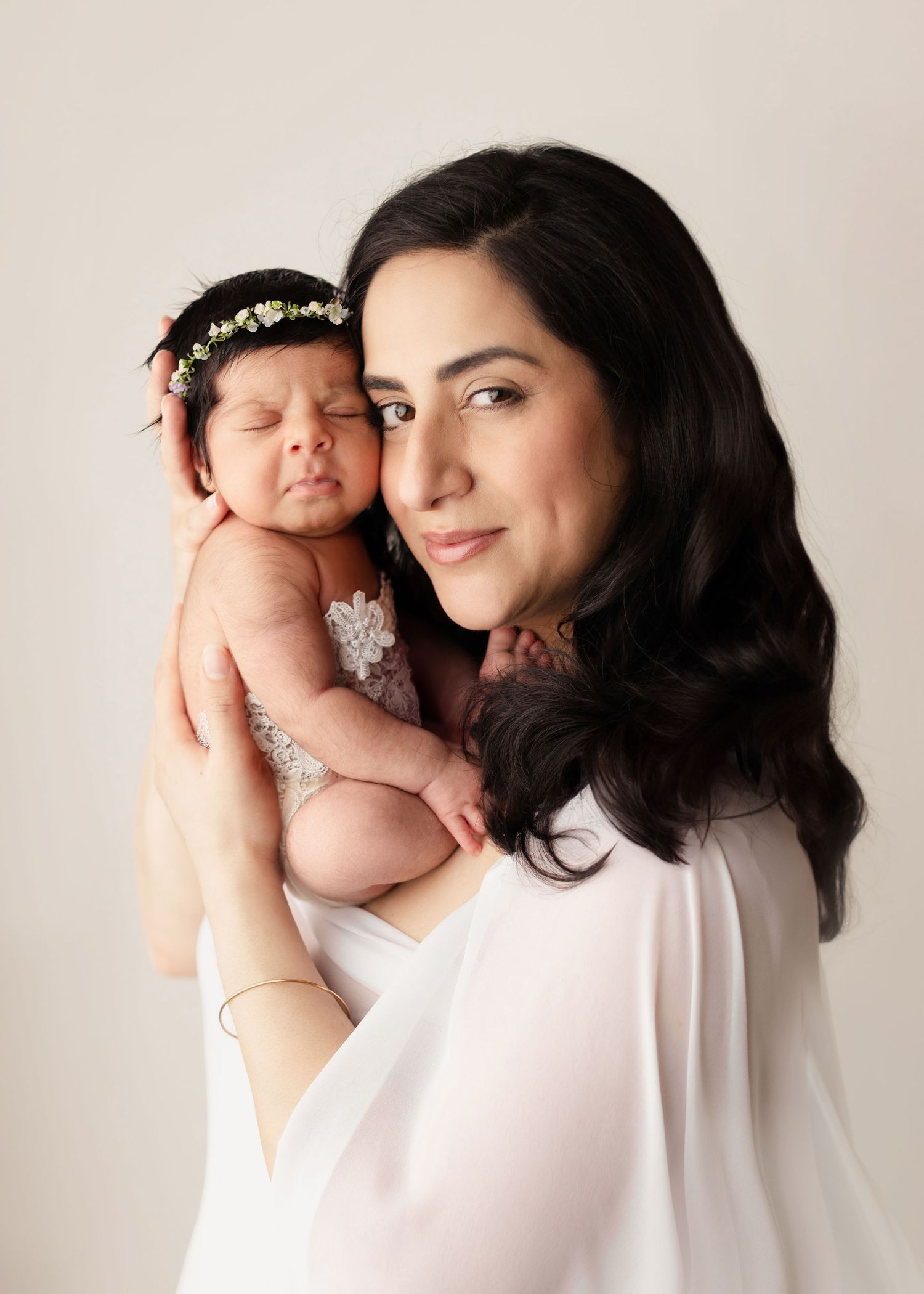 A woman in a white top holds and lovingly gazes at a sleeping newborn baby in a series of tender portraits. Elizabeth Lang Photography Surre