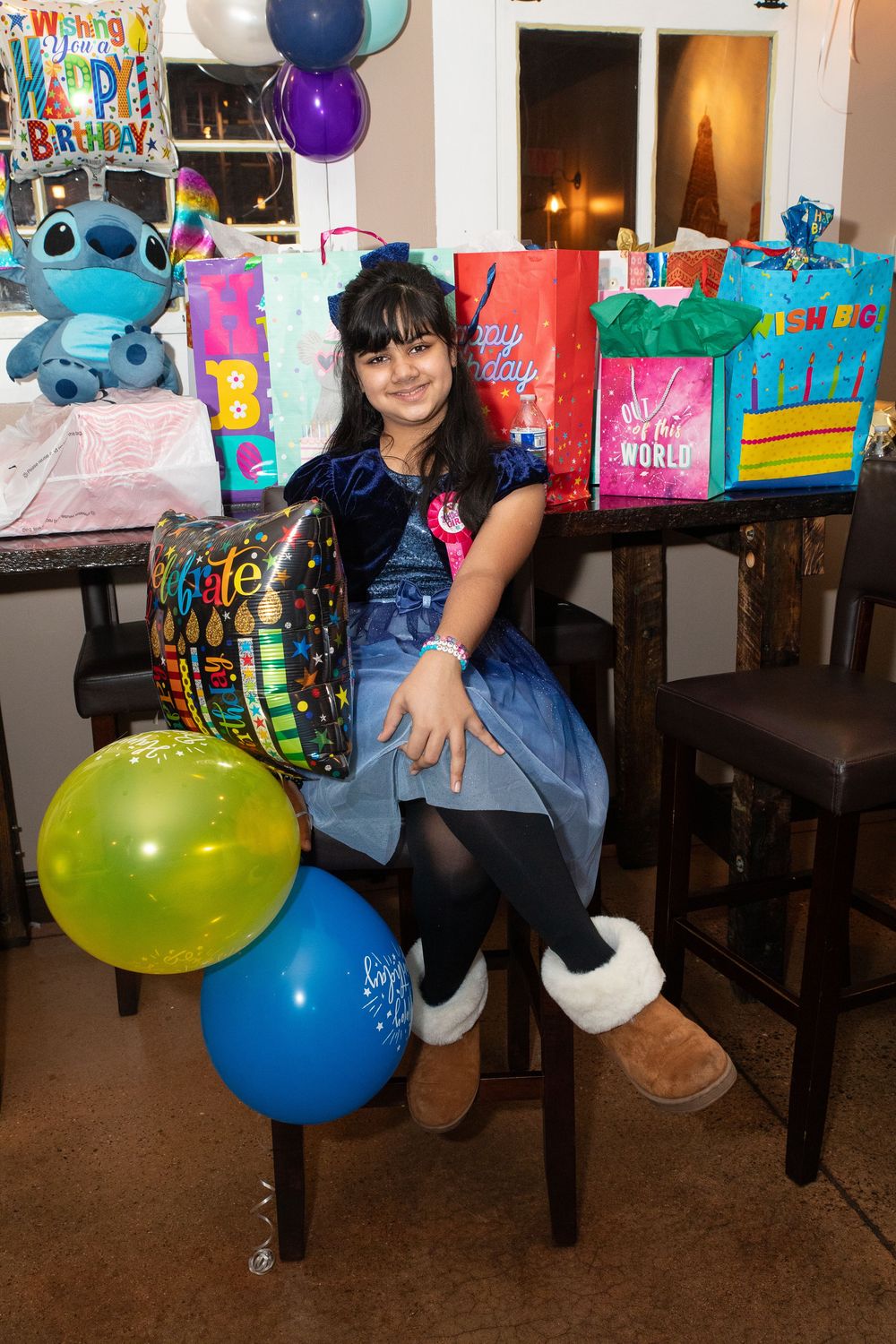 Colorful birthday celebration setup with Stitch themed decorations, balloons, and presents on a wooden table.