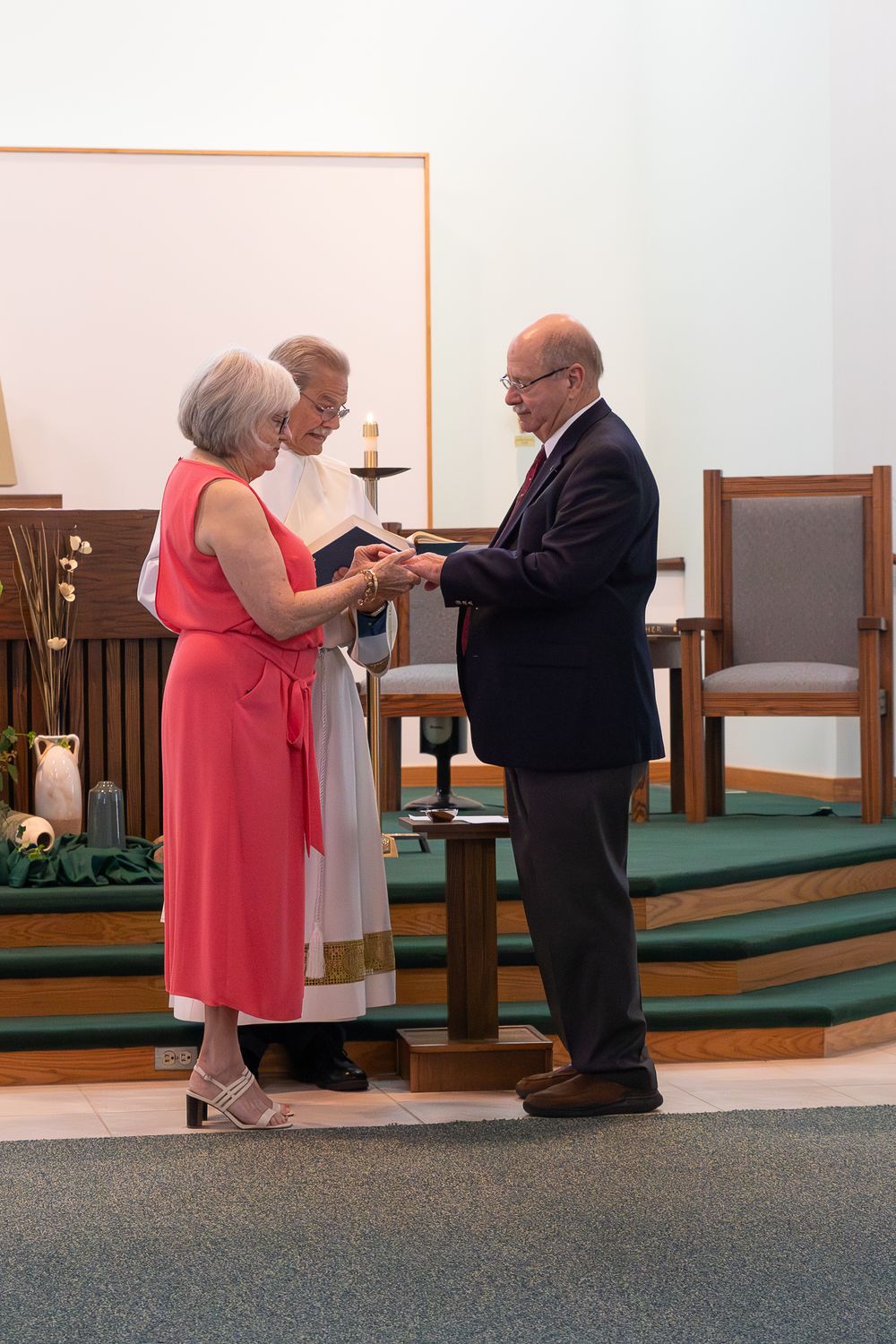 A couple in formal attire participates in a church ceremony at the altar.