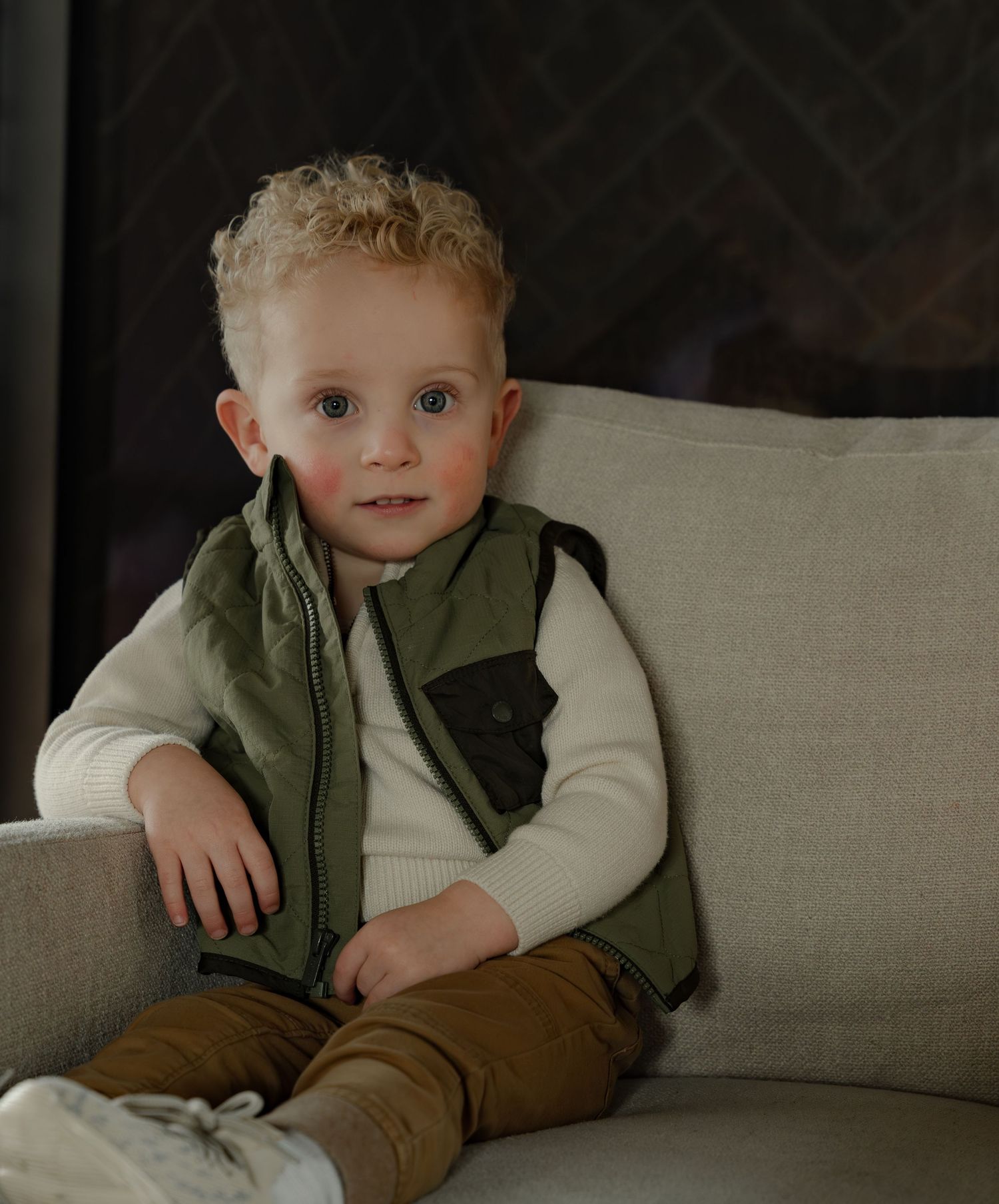 Professional children's portrait of a young boy in a green vest, captured during an indoor lifestyle session in Bloomington-Normal, IL.