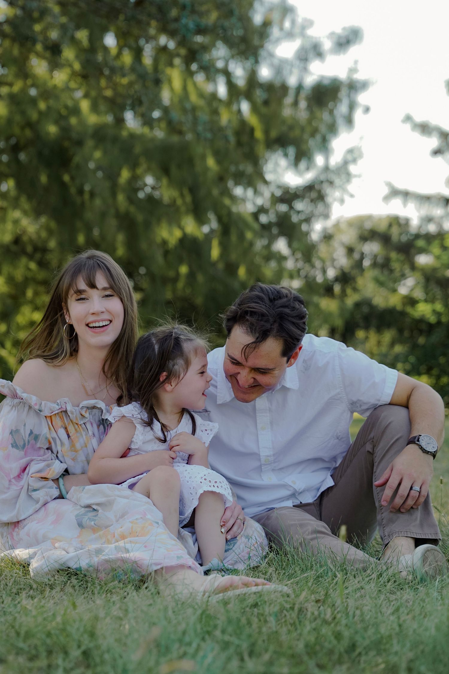 Airy outdoor family session in Central IL featuring a mother in a floral dress and a father holding their young daughter Goodphotography.co