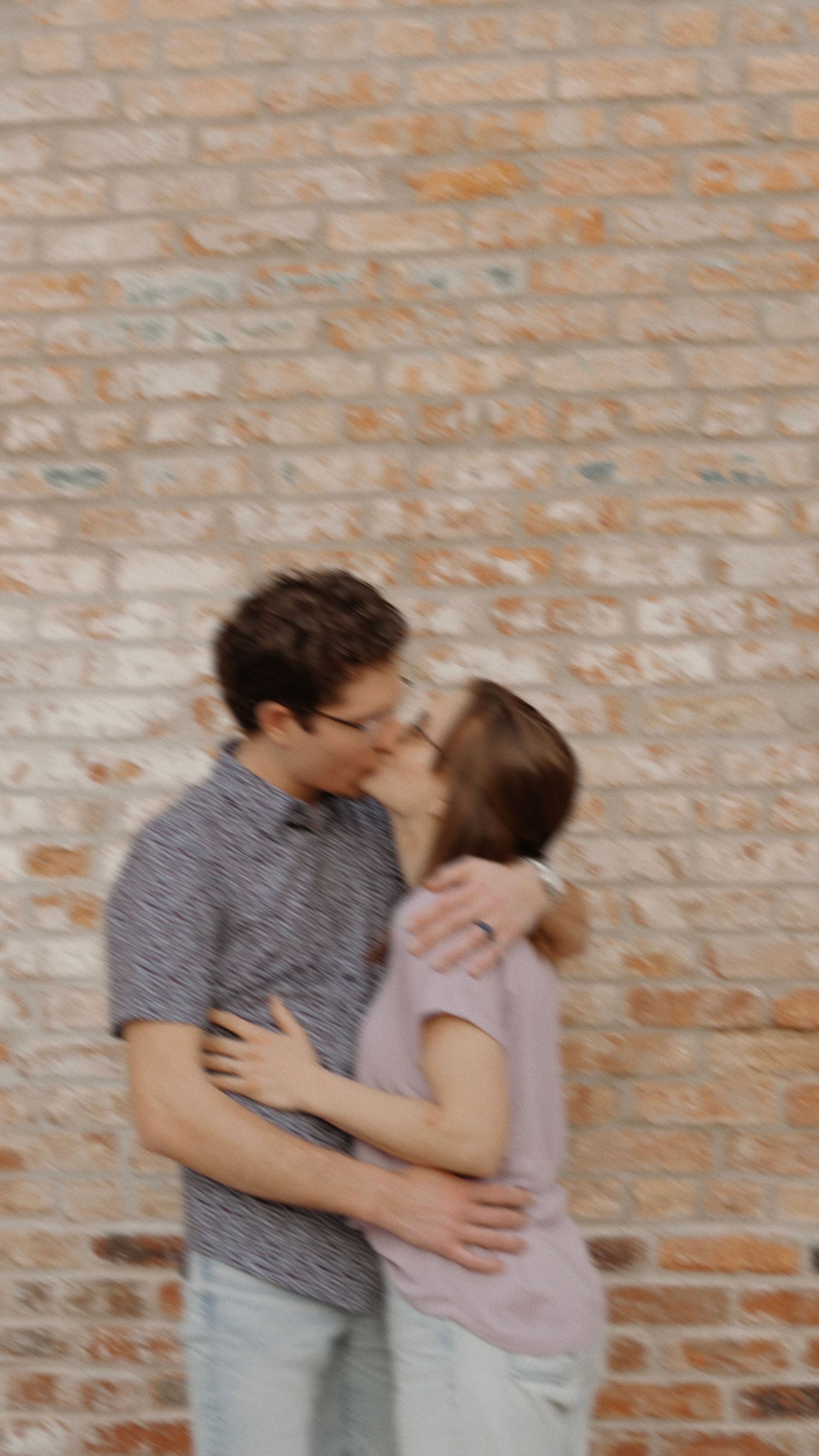 Motion-blur artistic couple's portrait against a brick wall in Lexington IL by Bloomington photographer Goodness Kabuswe.