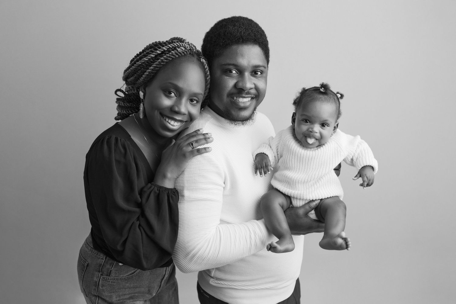 A series of black and white portrait photos showing a family embracing and smiling together at the studio in Victoria BC.