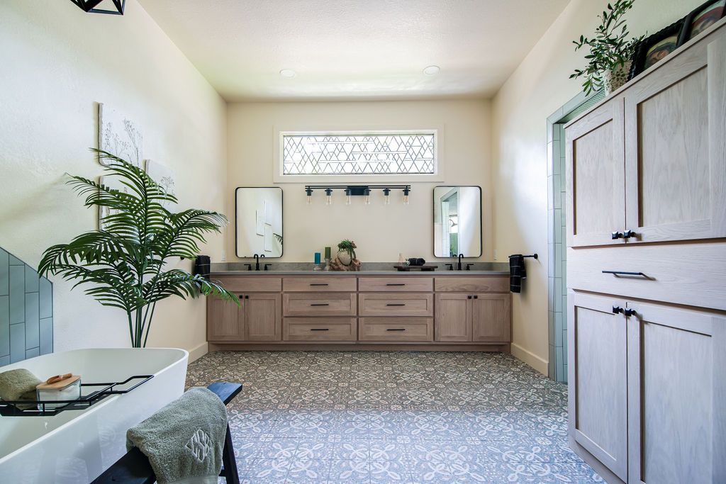Luxury bathroom remodel featuring a double vanity, large palm plant, and decorative window in Fredericksburg TX.