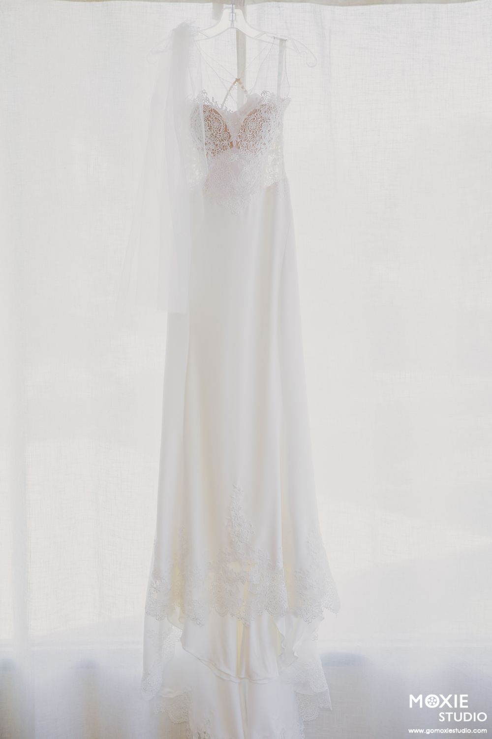 A collection of elegant white wedding dresses displayed on hangers against a light background.