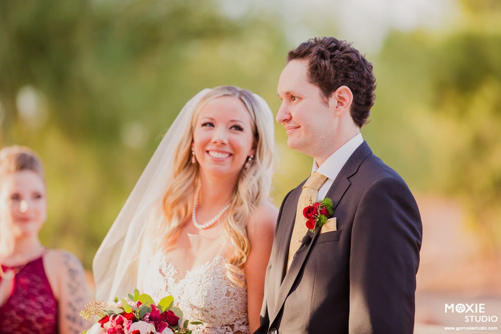 Wedding party poses outdoors in a garden setting with vibrant autumn flowers and greenery in the background.