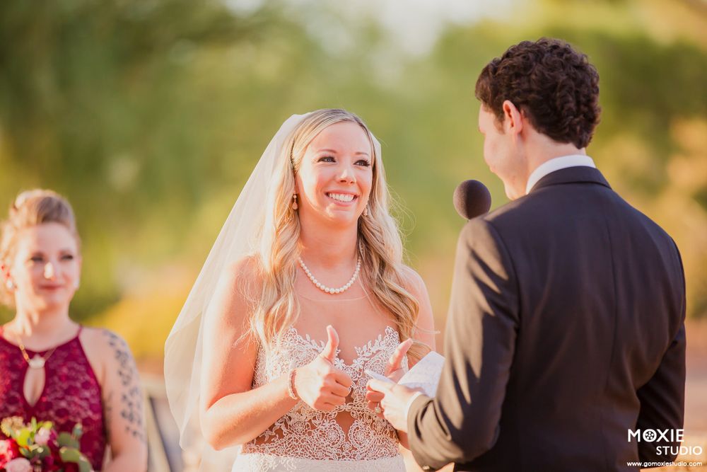 Wedding couple exchanges vows during an outdoor ceremony with golden sunlight filtering through trees in the background.