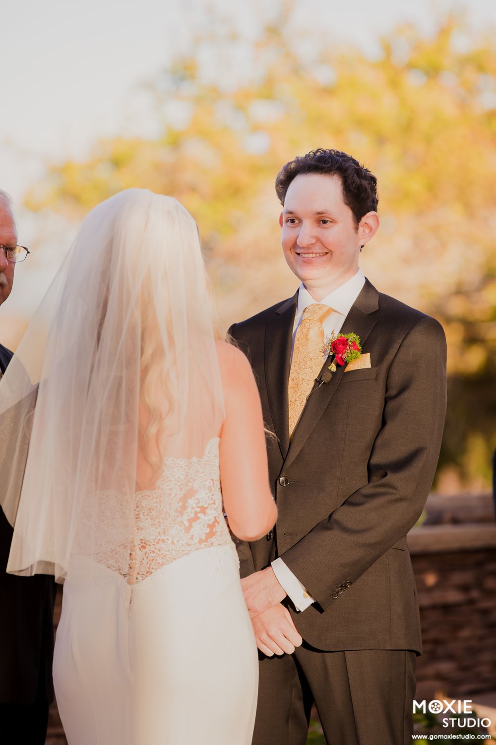 A wedding couple shares a romantic moment together in autumn with golden foliage in the background.