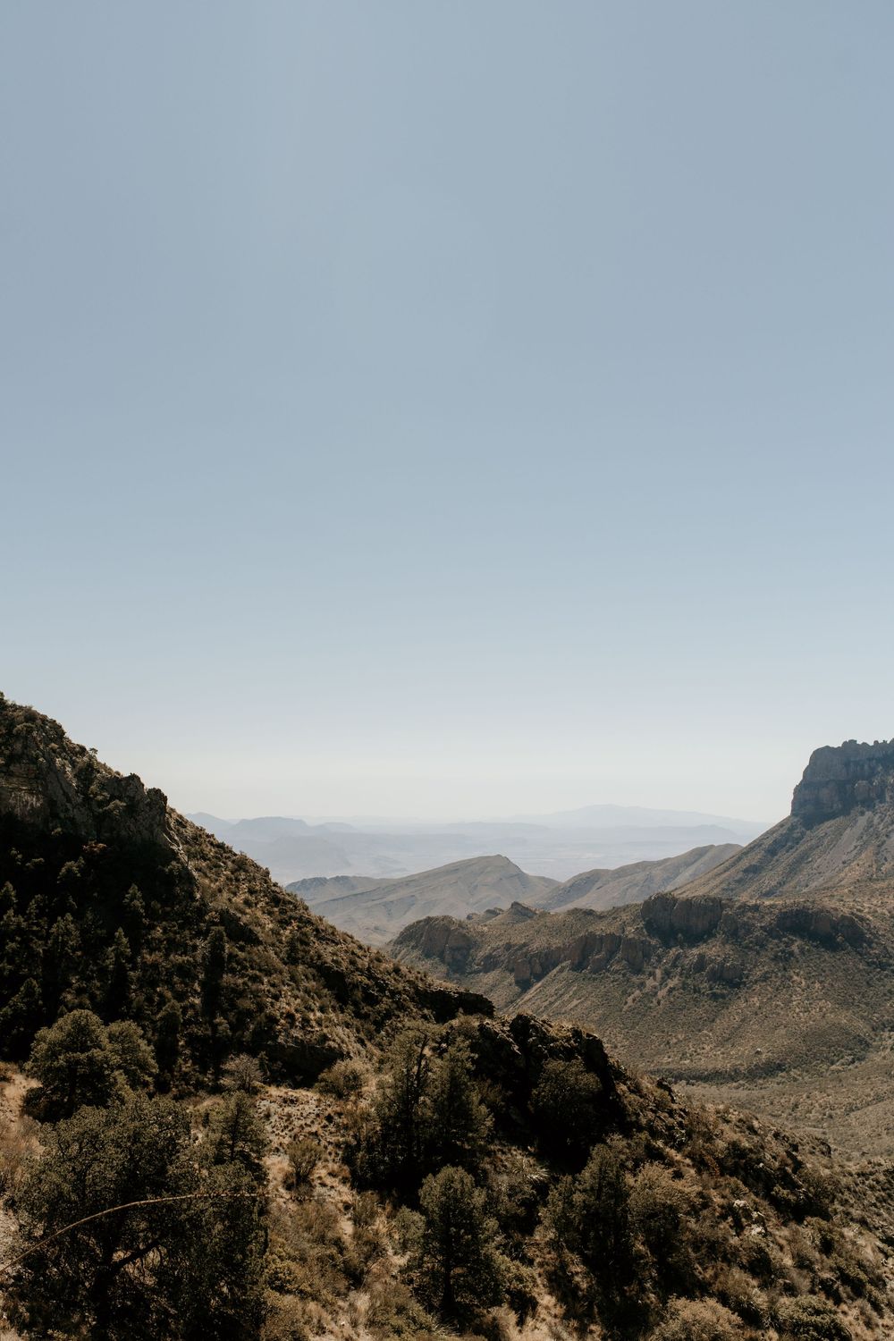 Scenic mountain landscape with rugged peaks and desert terrain under clear blue skies.