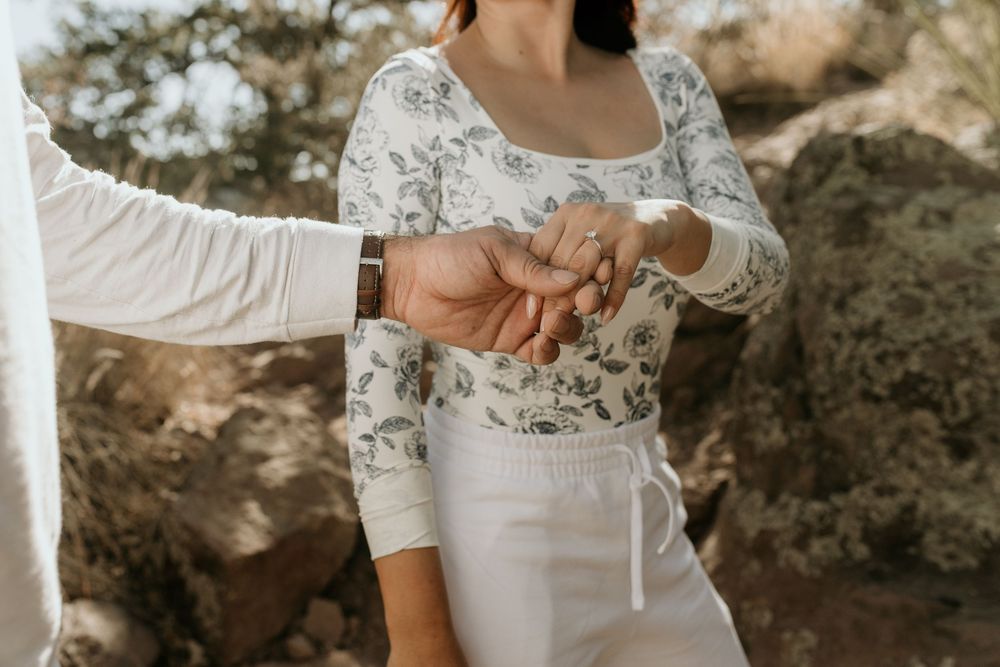 Close-up of hands showing engagement ring with lace sleeve detail.