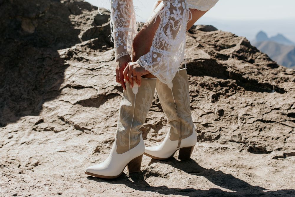 White cowboy boots and lace details shown against rocky mountain terrain.