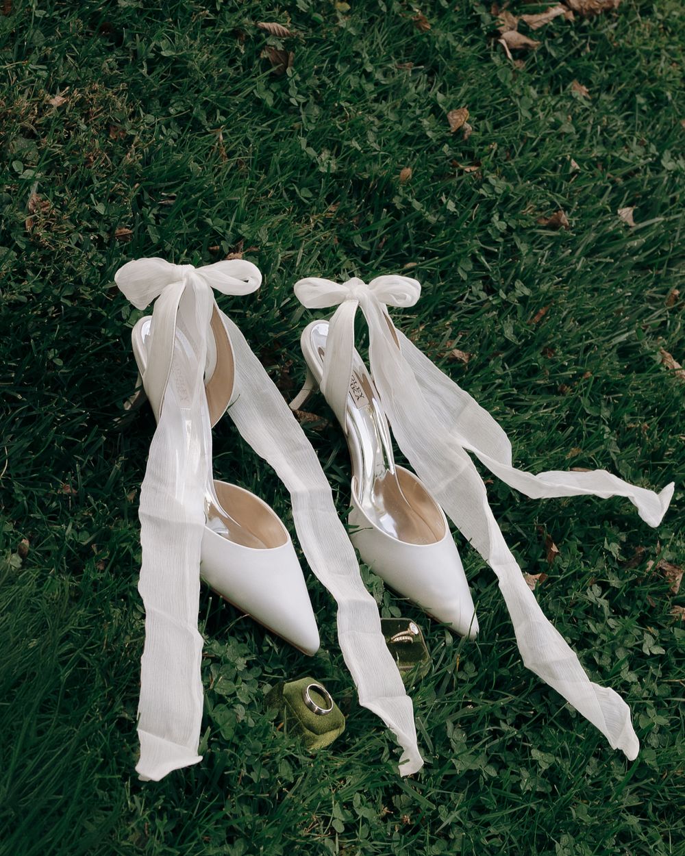 White ballet flats with delicate ribbon ties arranged in a graceful sequence on green grass background.