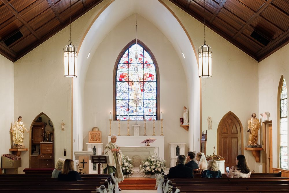 Interior view of a traditional church sanctuary with arched windows, wooden beams, and stained glass decorations.