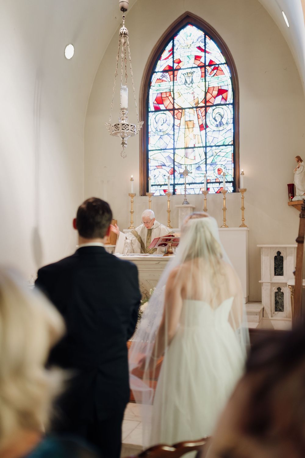 Interior of church with stained glass windows and arched ceiling during wedding ceremony.