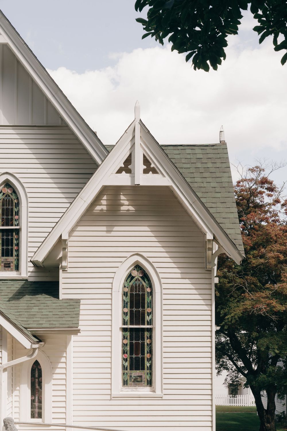 White Gothic Revival church exterior with pointed arched windows and siding shown in three overlapping architectural details.
