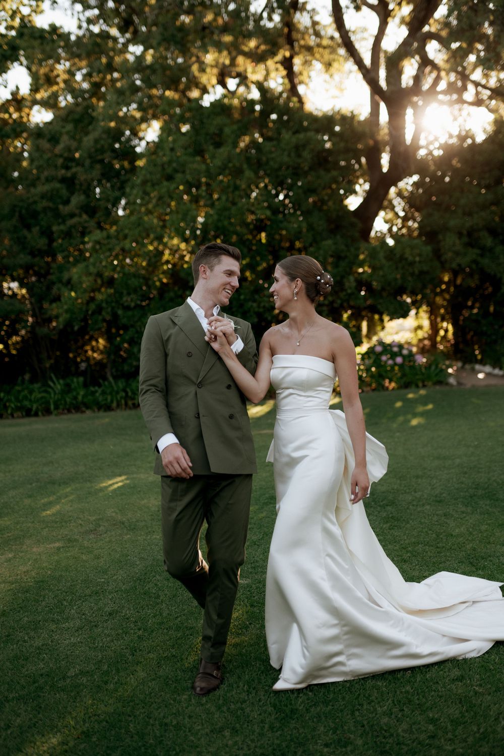 A couple shares a romantic moment on a lawn at golden hour.