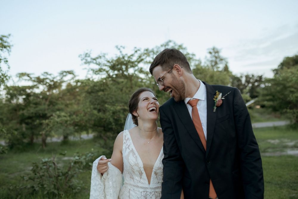 A couple in wedding attire share an intimate moment in a garden setting during their special day.