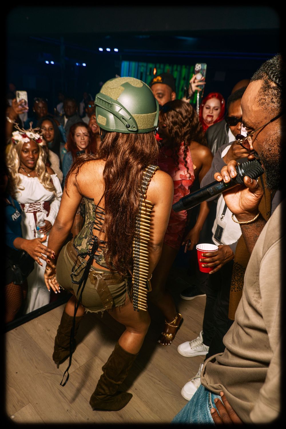 Party goers dance and socialize at a nightclub event with dramatic lighting and festive atmosphere.
