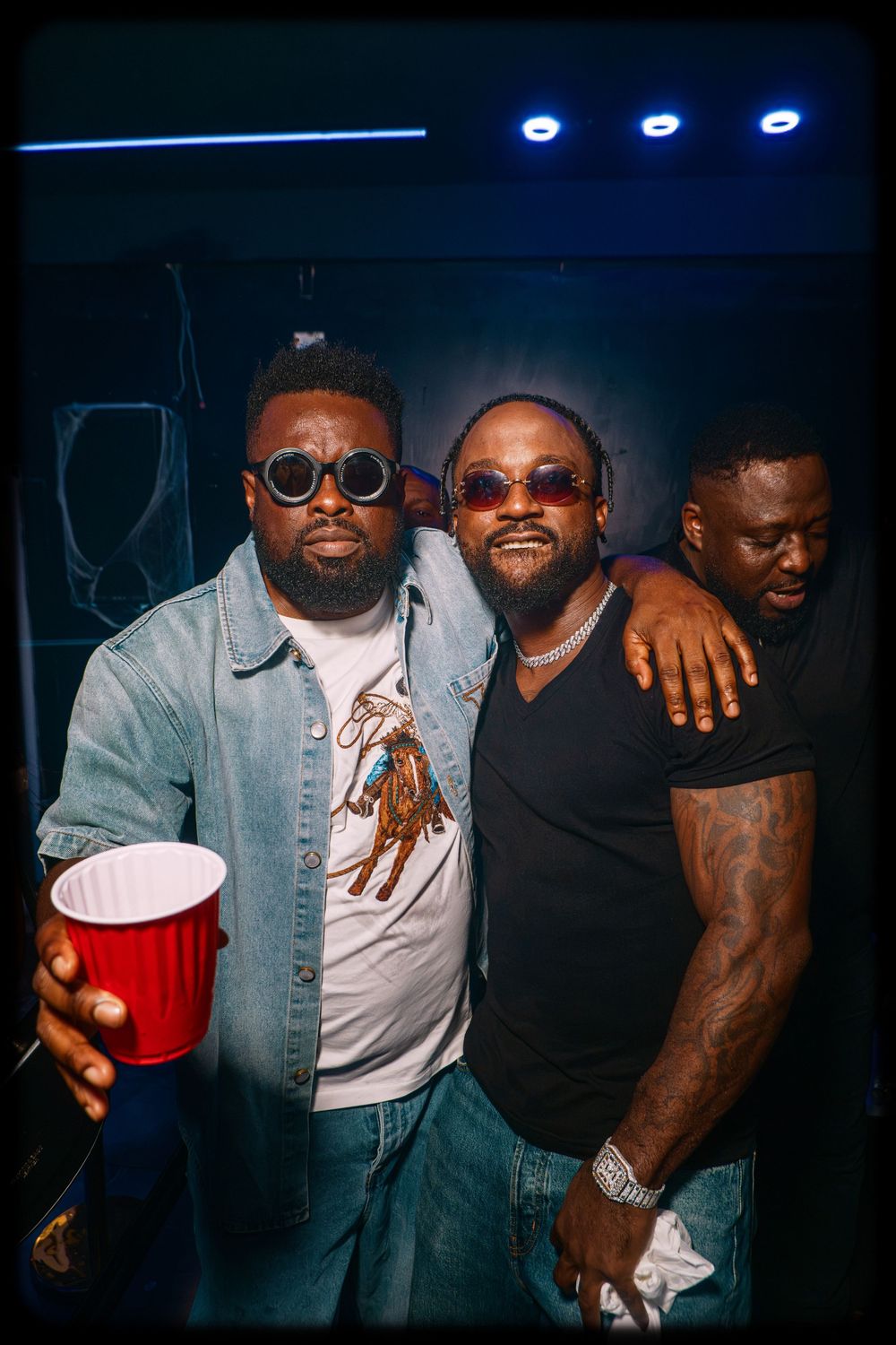 Group of friends hanging out at a nightclub in casual attire enjoying drinks and social atmosphere.