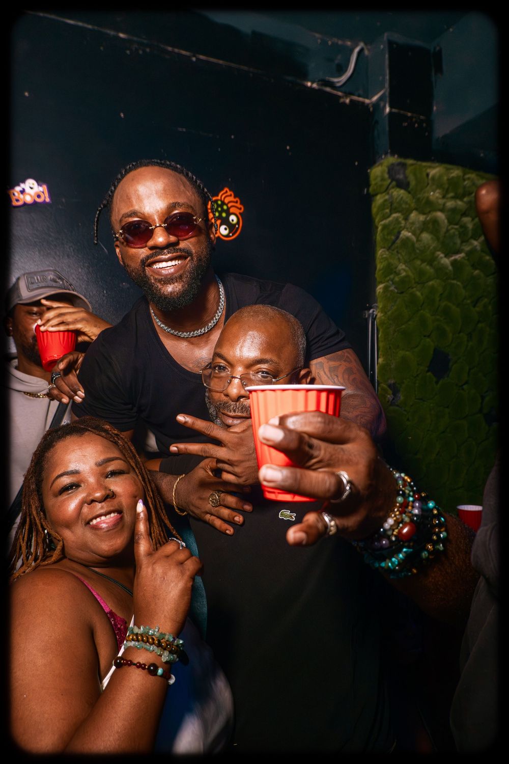 A group of friends share laughter and red cups at a nighttime gathering with joyful expressions.