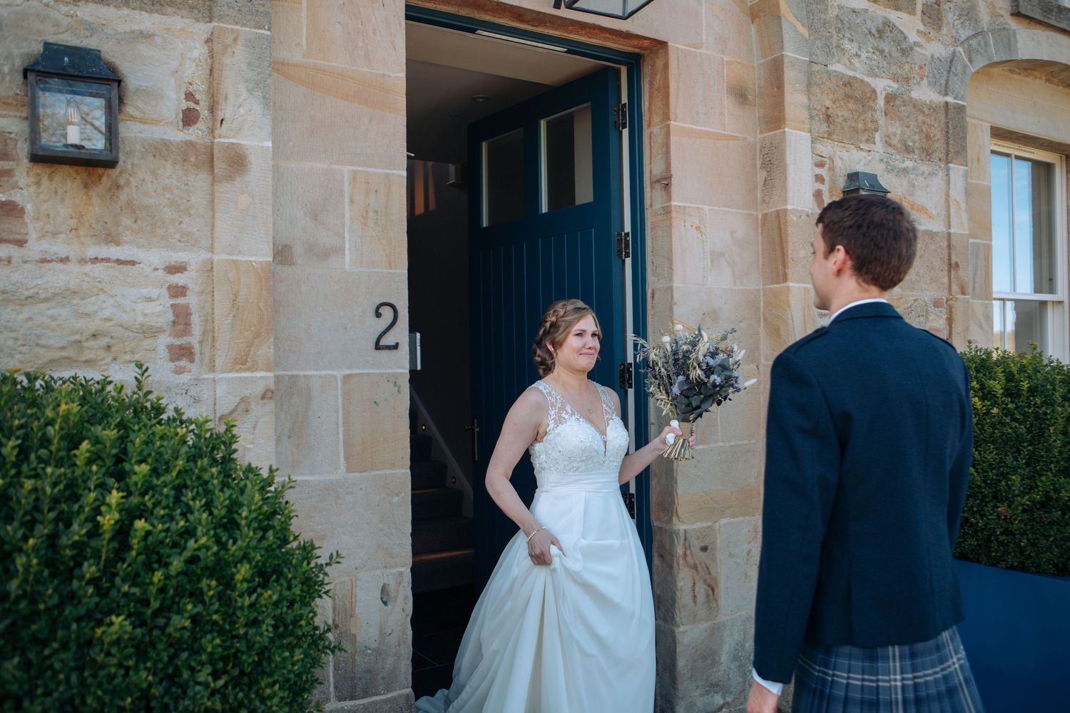 Bridesmaids in soft sage green dresses hold white bouquets while getting ready for a wedding celebration.