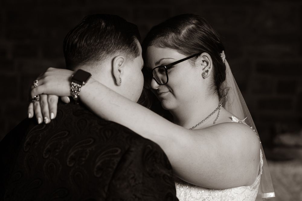 A romantic black and white photo of a couple embracing during their first dance at a wedding reception.