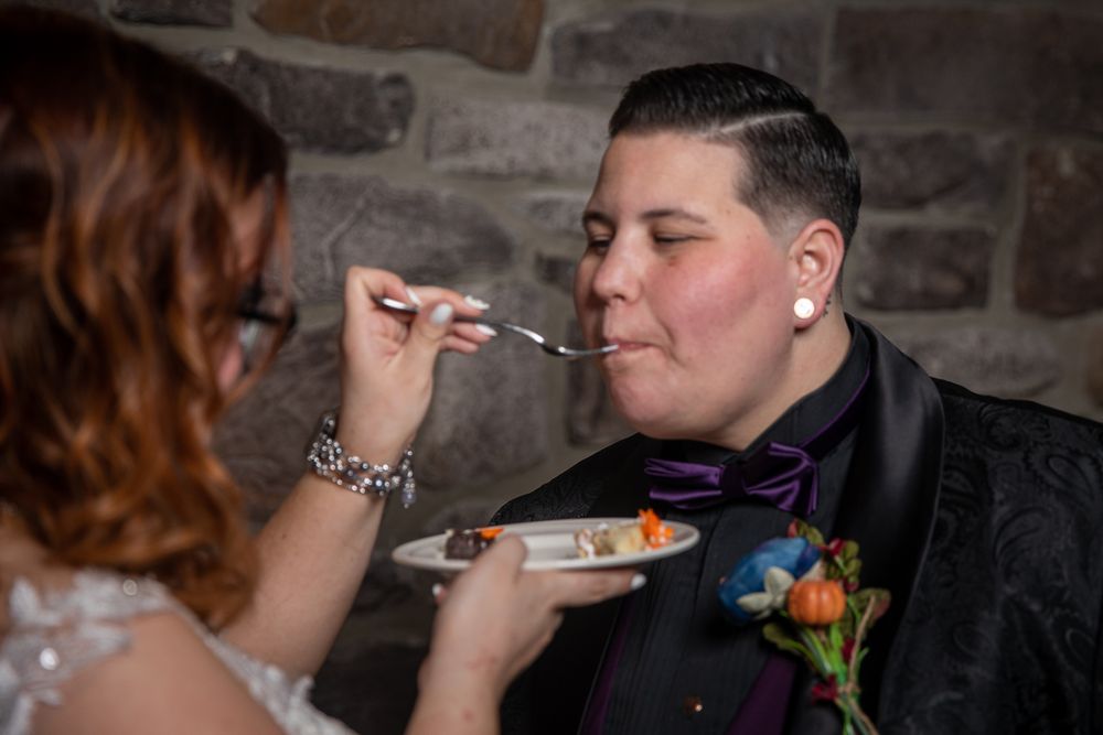 A couple shares an intimate moment during their wedding ceremony in front of a stone wall.