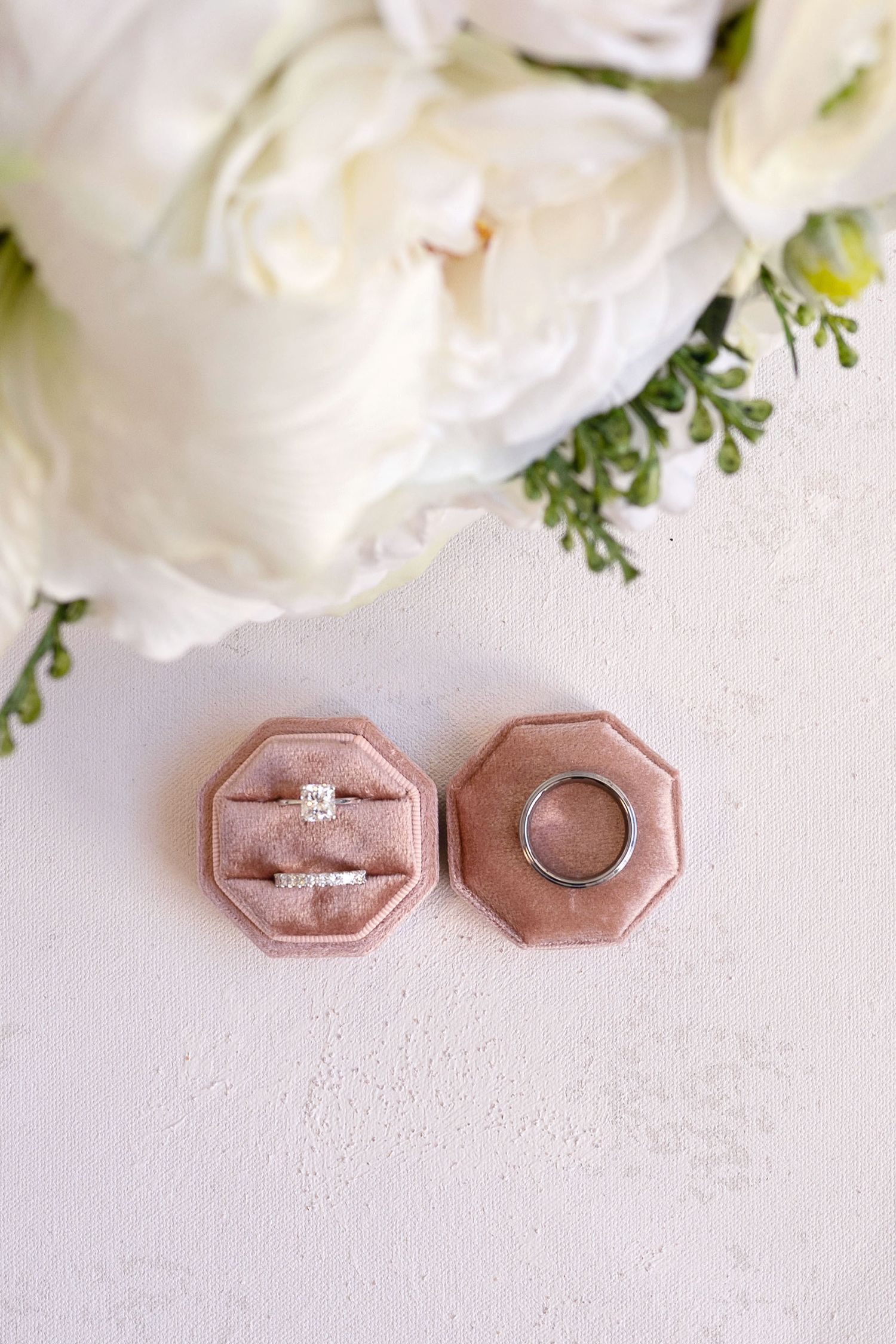 Close-up view of elegant wedding stationery with engagement rings and soft natural lighting.
