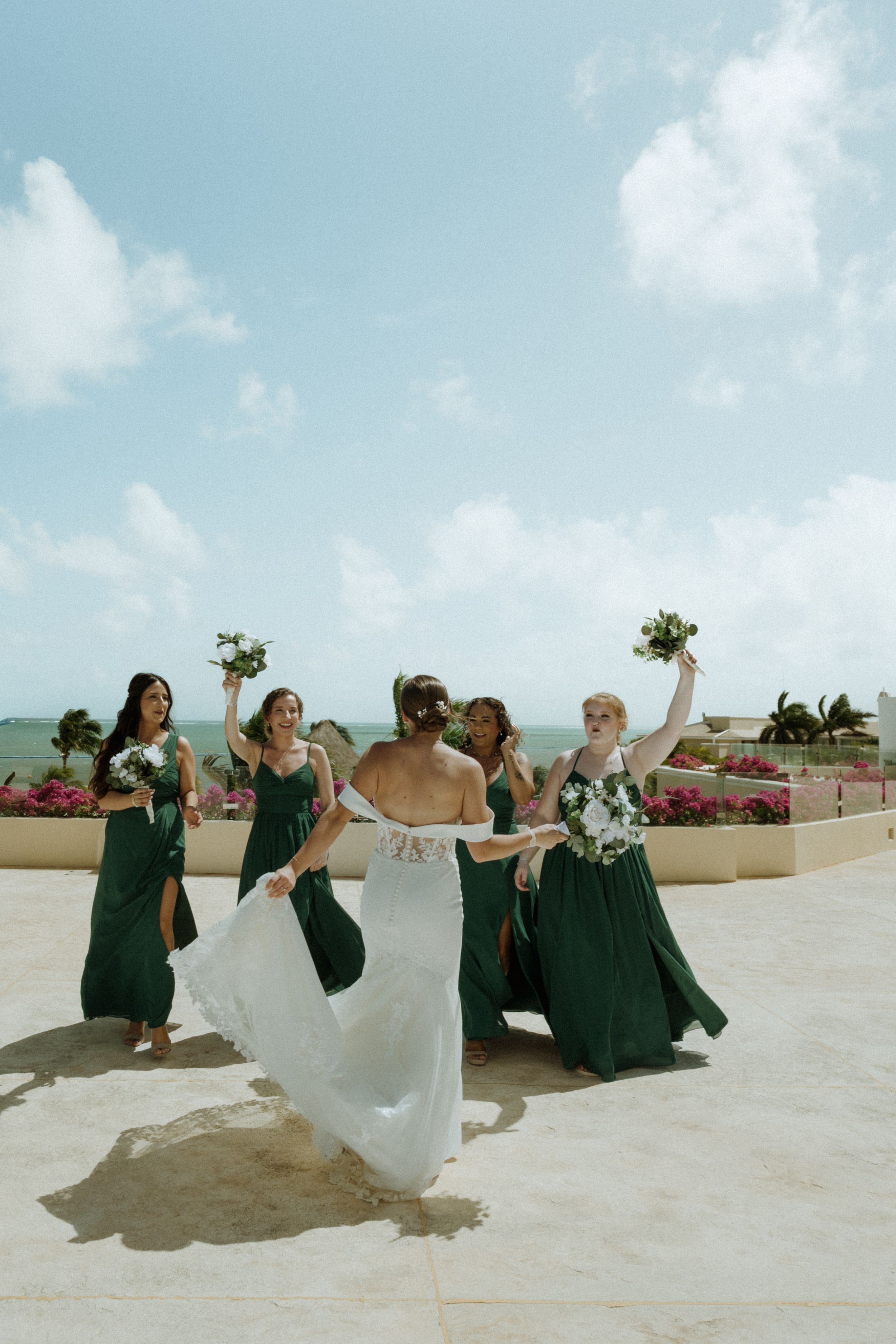 A sequence of wedding party photos showing playful poses on a white rooftop terrace against a blue sky.