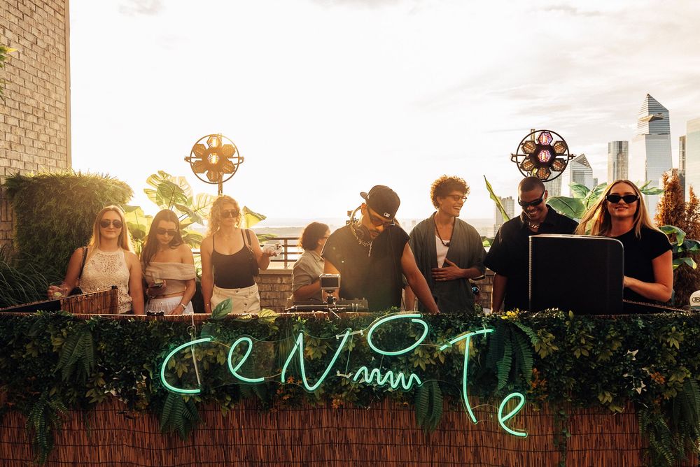 People gather at an outdoor event during sunset with string lights and decorative elements creating a warm ambiance.