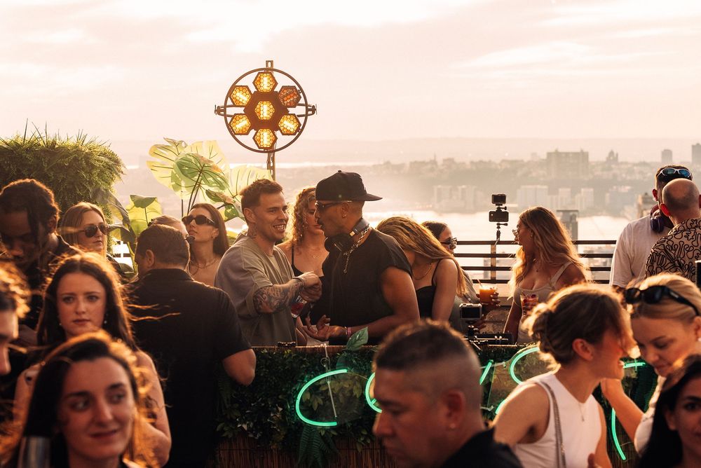 People enjoying an outdoor social gathering at dusk with glowing lights in the background.