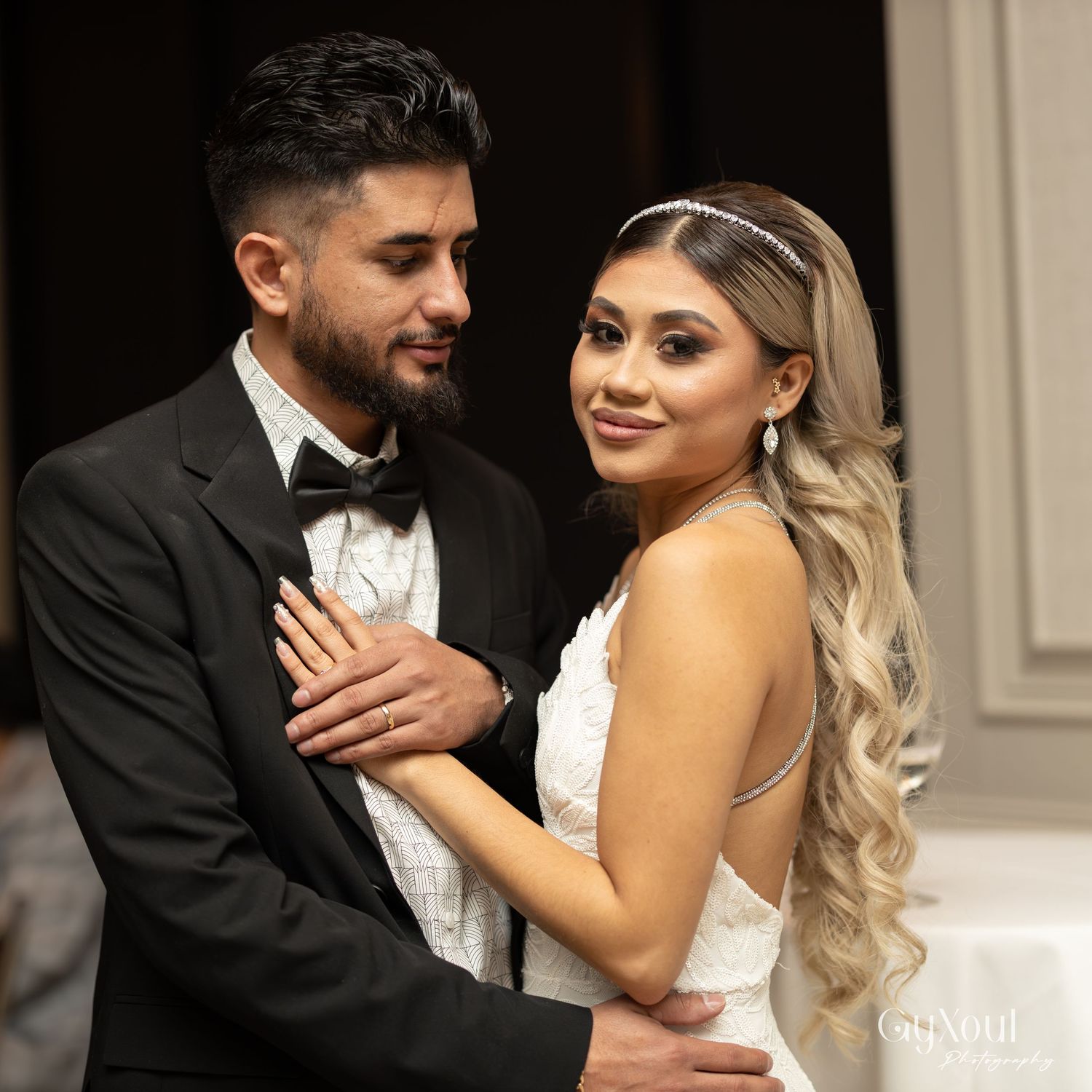Couple in formal wedding attire embracing and dancing together in an elegant setting.