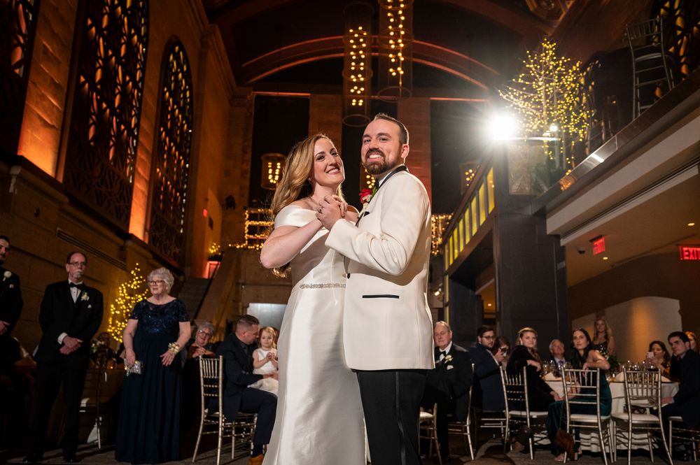 Indoor wedding reception dance with warm lighting and elegant venue decorations.