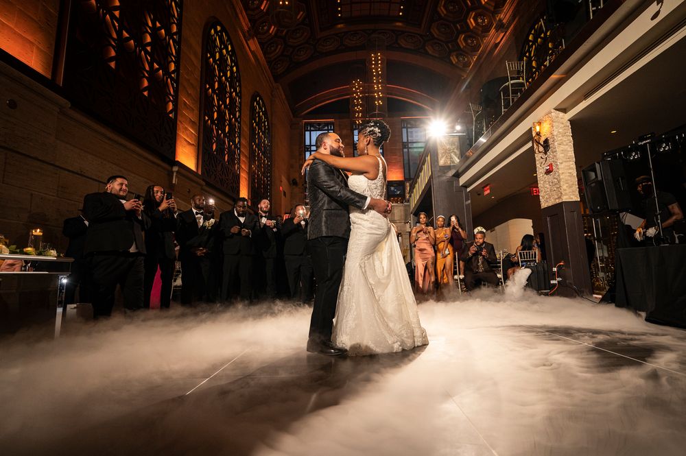 A wedding couple dances on a dark wooden floor while guests watch from the perimeter of a Union Trust wedding