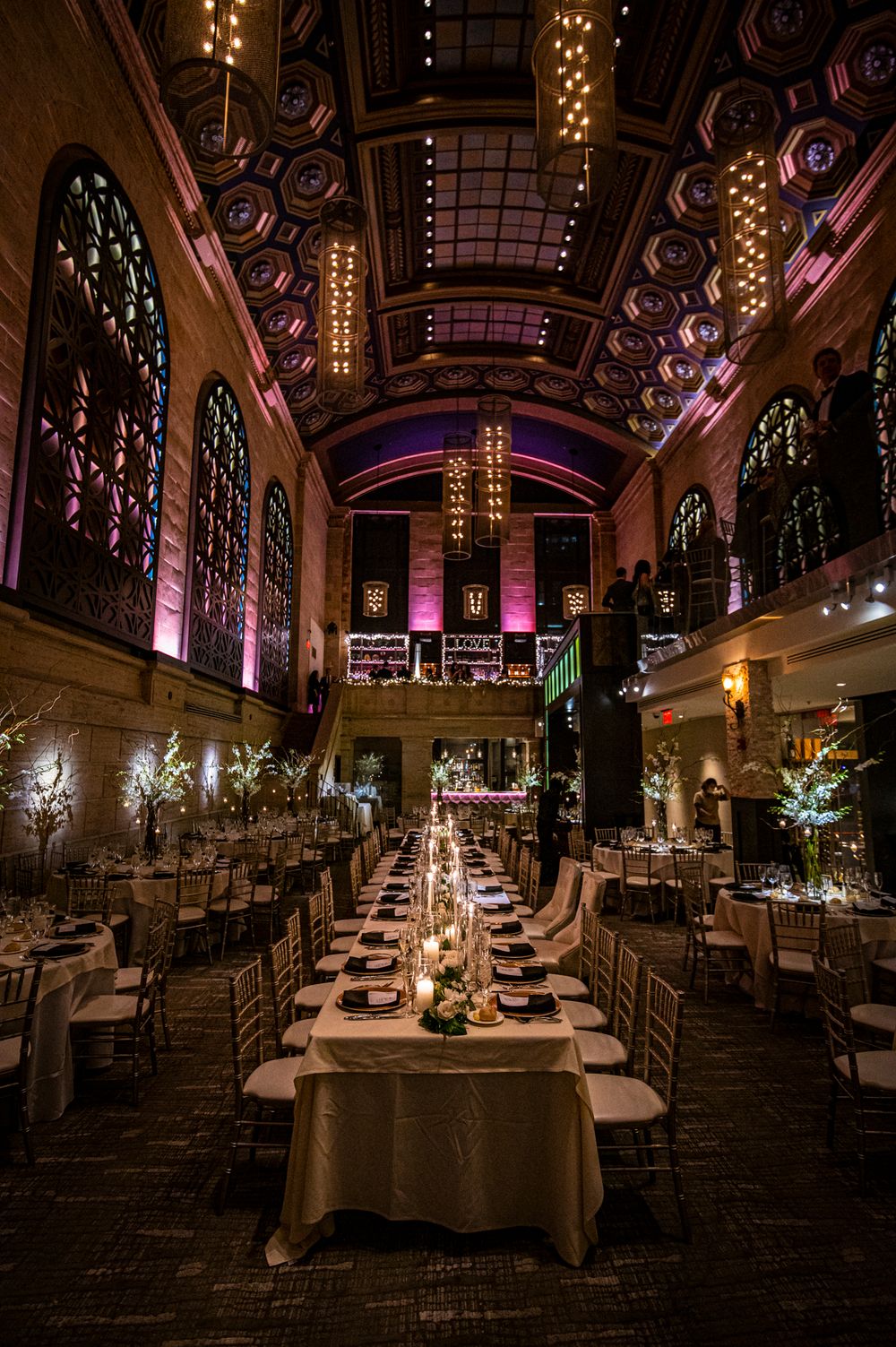 Elegant wedding reception venue at Union Trust in Philadelphia with stained glass windows, and long banquet tables set for dinner.