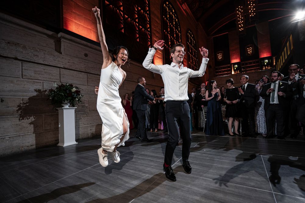 Wedding guests dance and celebrate on a dimly lit dance floor during an evening reception celebration.
