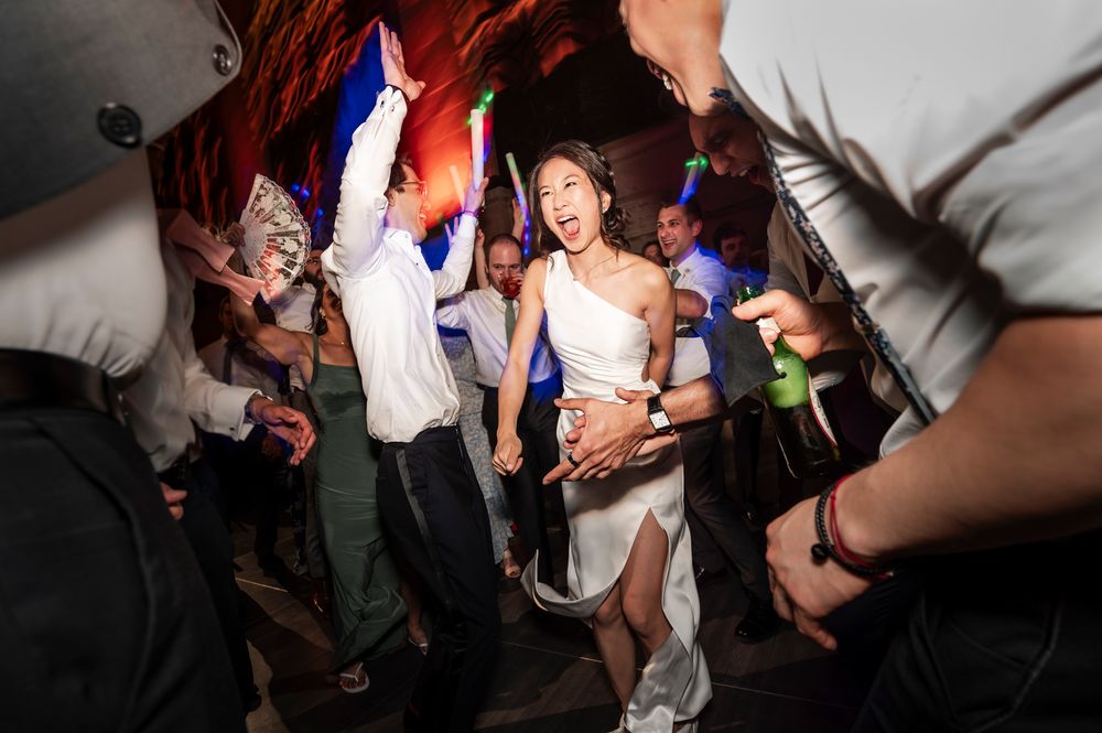 People dancing energetically at a wedding reception with dramatic lighting and shadows at a Union Trust wedding