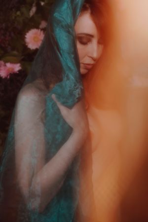 Dreamy portrait with turquoise fabric and soft orange light effects.
