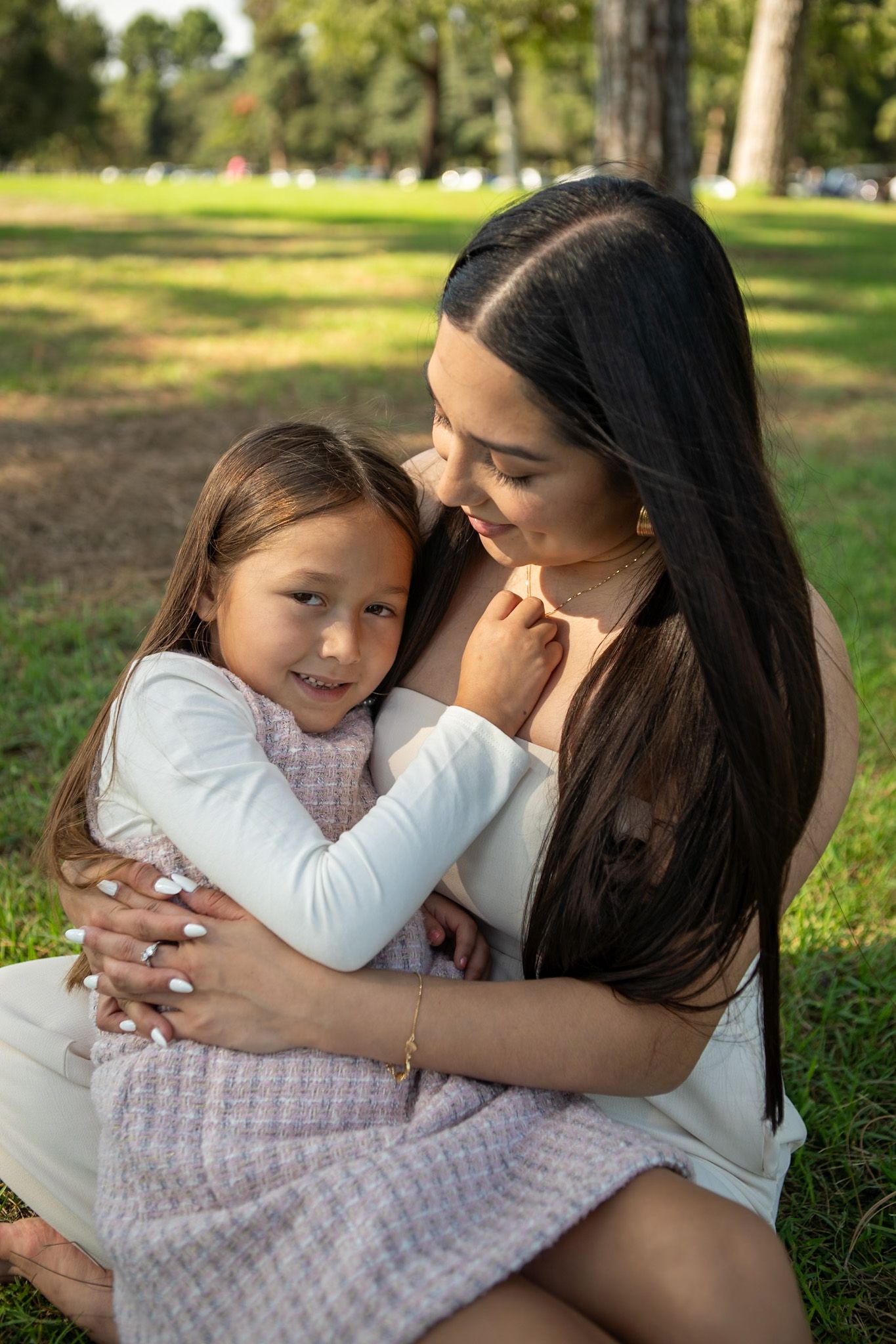 A tender moment shared between two people embracing on green grass in a sunny park setting.