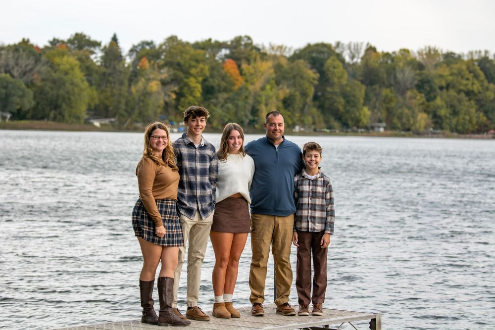 A group stands together in shallow water at the edge of a lake during an outdoor photo session.