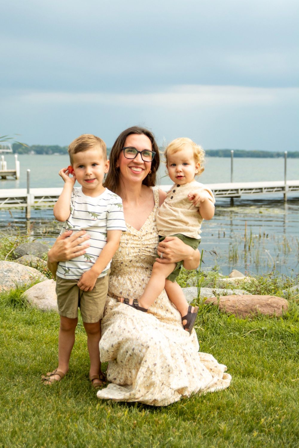 Family enjoying a sunny day by the waterfront on grassy lawn with scenic lake view in background.